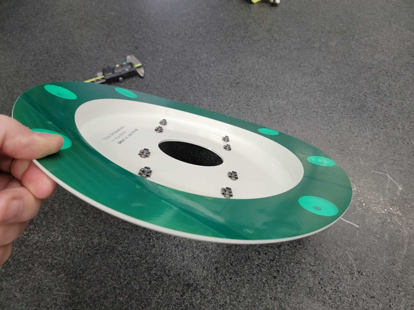 Machined disc with green and white finish held in hand