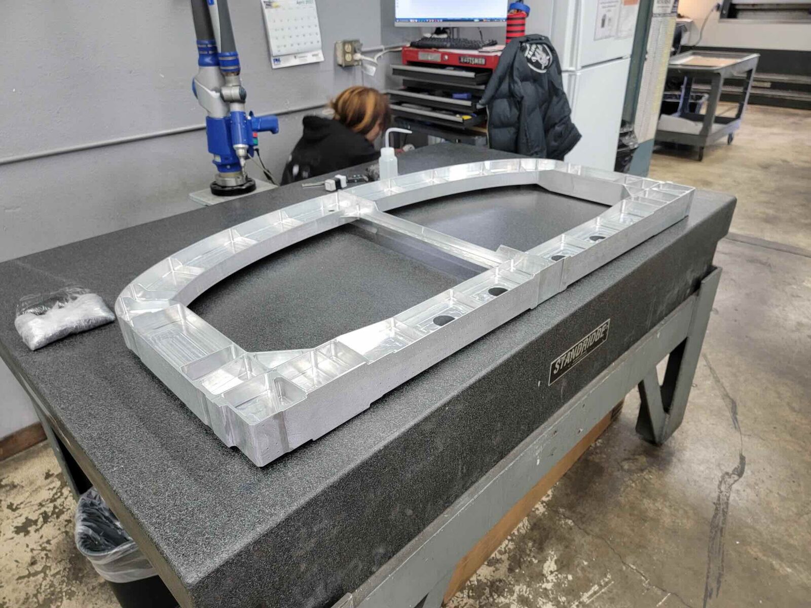 Inspector measuring a large aluminum frame with a CMM arm