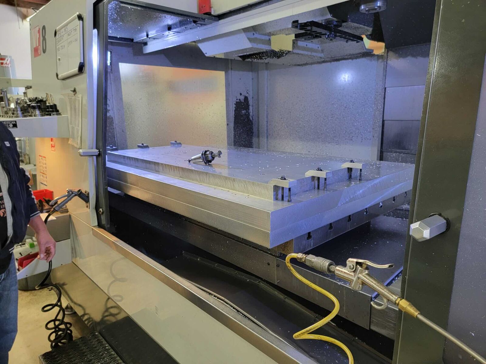 Large aluminum plate being machined inside a CNC machine