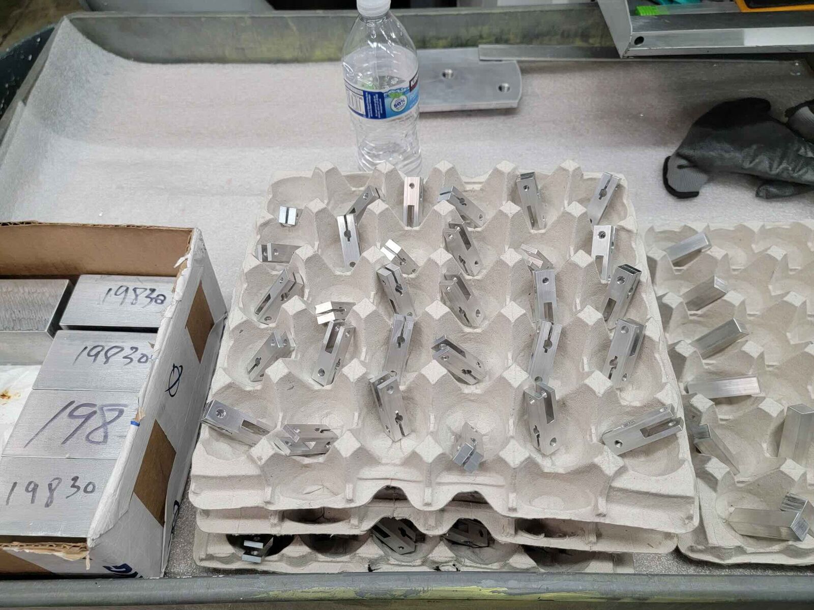Batch of small machined aluminum parts in trays