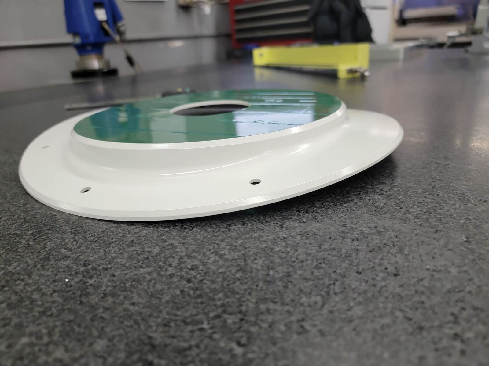 Machined ring with white and green finish on granite table