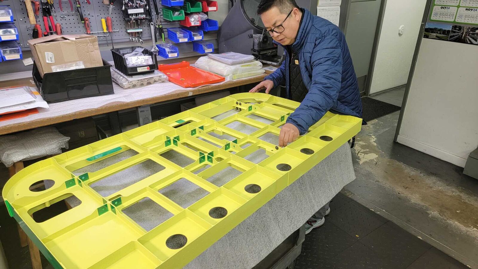 Machinist handling a large yellow coated fixture plate