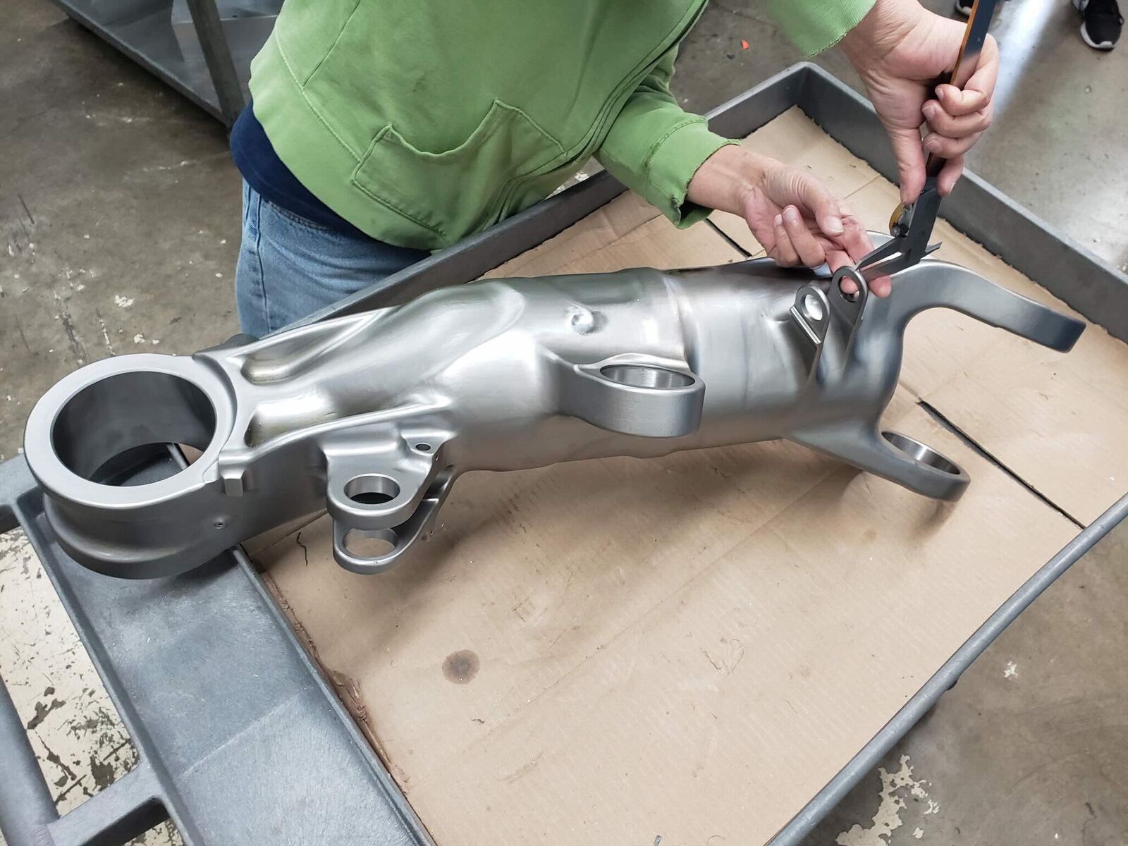 Machinist deburring a large cast aluminum arm