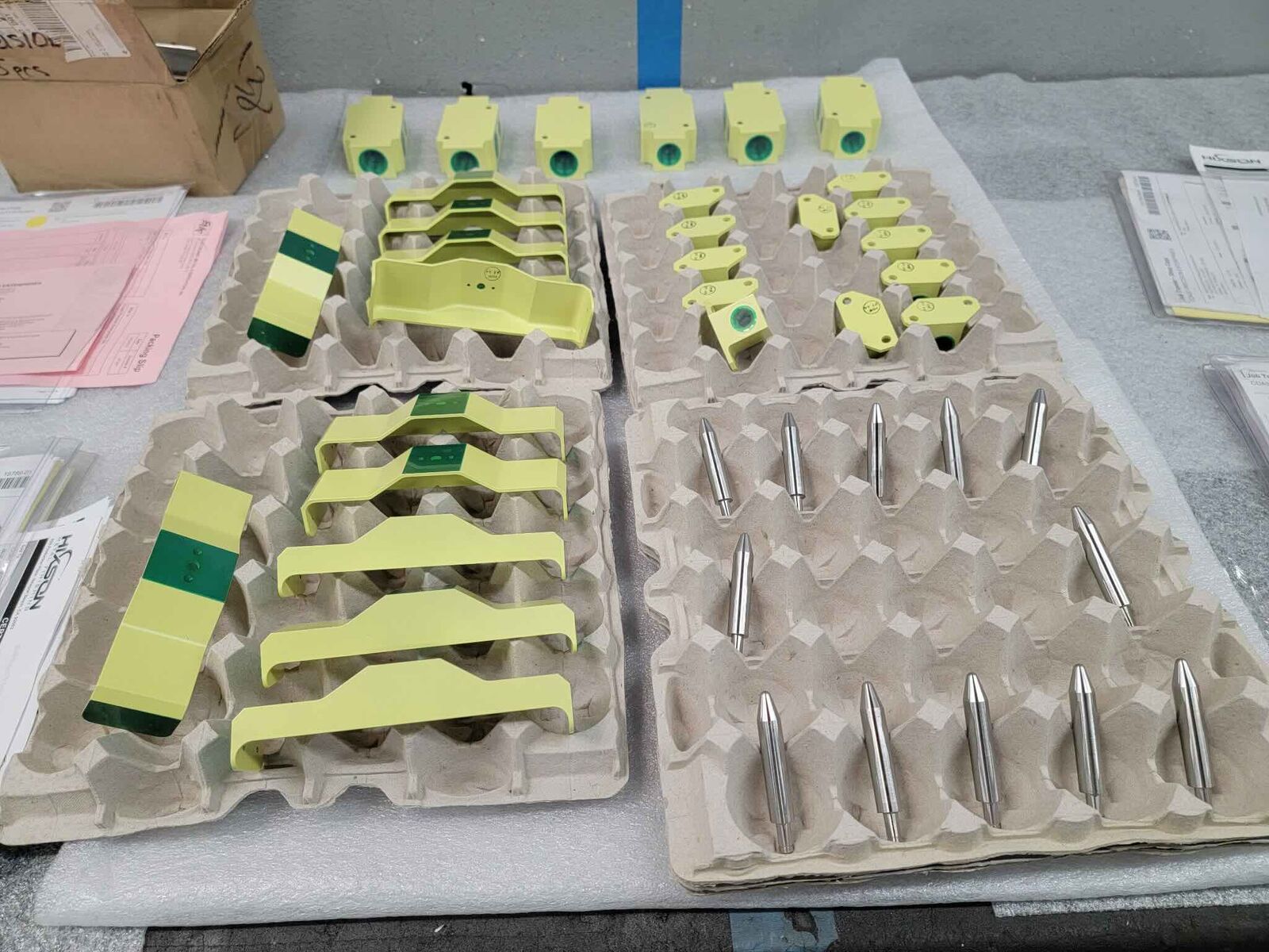 Batch of coated yellow and green parts packed in trays